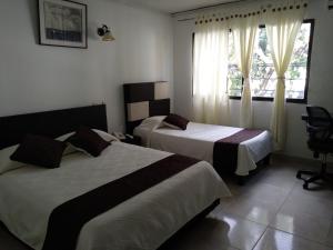 Una habitación de hotel con dos camas y una ventana. en Hotel Nova Park, en Arauca