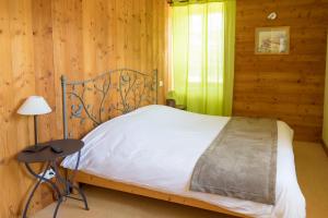 a bed in a wooden room with a lamp and a table at Auberge le Sabot de Vénus in Méaudre