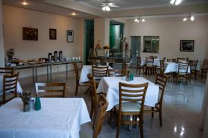 a restaurant with white tables and chairs and a counter at Apart Hotel Água Limpa in Prados