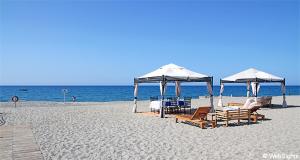 una playa con sillas y sombrillas y el océano en Matthias Hotel Apartments, en Adelianos Kampos