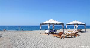 a beach with chairs and umbrellas and the ocean at Matthias Hotel Apartments in Adelianos Kampos