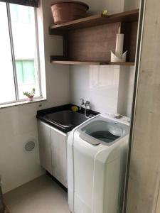una lavadora en una cocina con fregadero en Residencial Varadero, en Bombinhas