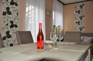 a bottle of wine sitting on a table with two wine glasses at Győrszem Apartman in Győr