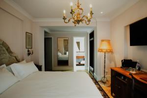 sypialnia z dużym białym łóżkiem i żyrandolem w obiekcie Ebel Boutique Hotel w Tiranie