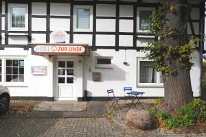 a white building with a sign in front of a tree at Hotel Zur Linde in Salzgitter