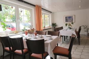 un comedor con mesas y sillas blancas y ventanas en Hotel Zur Linde, en Salzgitter