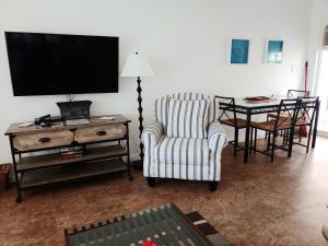 a living room with a tv and a chair and a table at Sunrise Ocean Suites in Pompano Beach