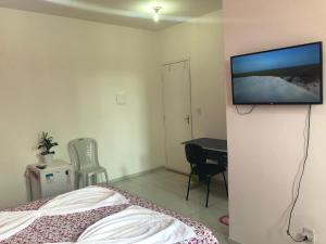 um quarto com uma cama e uma televisão de ecrã plano na parede em Pousada Sol Nascente em Barreirinhas