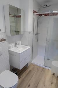 y baño blanco con lavabo y ducha. en Modern duplex with garden en Bruselas