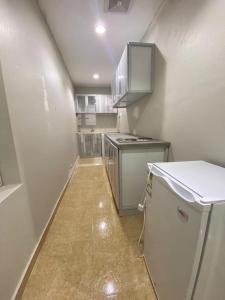 Una pequeña cocina con gabinetes blancos y un refrigerador. en Masaken alkenan, en Yanbu