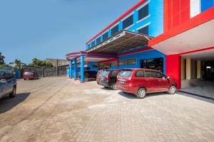 two cars parked in a parking lot in front of a building at OYO 1633 Hotel Darma Nusantara 3 in Makassar