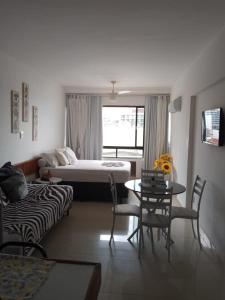 sala de estar con cama, mesa y sillas en Farol Barra flat 412, en Salvador
