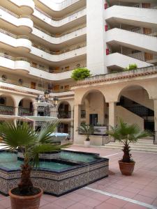 a building with a fountain and palm trees in a courtyard at Apartamentos Córdoba Arysal in Salou