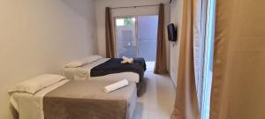 a room with two beds and a tv and a window at Hi Adventure in Florianópolis