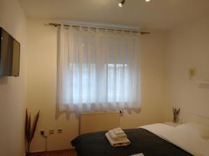 a bedroom with a bed and a window with white curtains at Apartment Nina in Varaždin