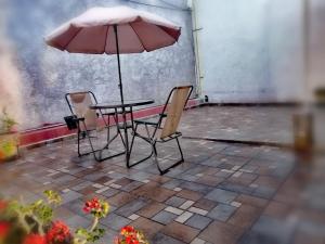 mesa y 2 sillas con sombrilla en Hostal Maple, en Querétaro