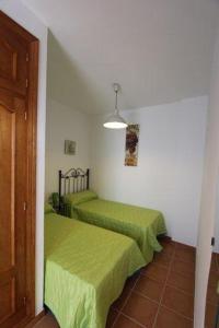 two beds in a room with green sheets at Casa María en el centro Nerja in Nerja