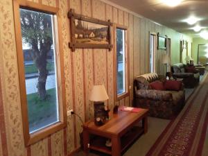 a living room with a couch and a table and two windows at Hostal Don Pedro in Puerto Natales