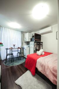 Sangubashi Studio Apartment with private entrance في طوكيو: غرفة نوم بسرير وبطانية حمراء وطاولة