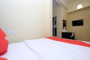 Un dormitorio con una cama roja y blanca y una silla en OYO 44029 Tudor Home Inn en Cameron Highlands
