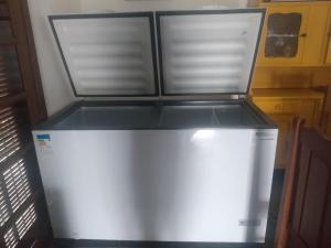 a white refrigerator in a kitchen with two windows at Chacara Recanto do Carlão in Biritiba-Mirim