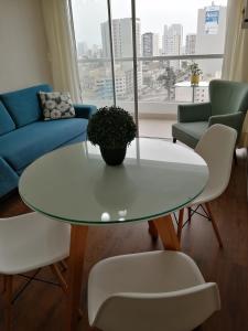 Una sala de estar con una mesa y sillas blancas. en Departamento BH South, en Lima