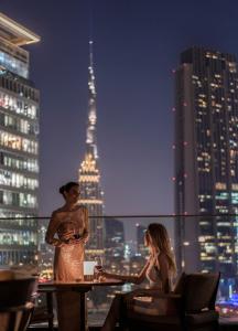 a man and a woman sitting at a table on a rooftop at Four Seasons Hotel Dubai International Financial Centre in Dubai