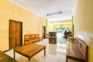 a living room with wooden benches and a tv at SPOT ON 2422 Hotel Moga Sari in Situbondo