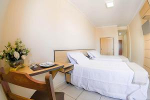 ein Hotelzimmer mit 2 Betten und einem Tisch mit Blumen in der Unterkunft Antico Plaza Hotel in Taubaté