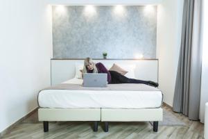 Eine Frau, die mit einem Laptop auf einem Bett liegt. in der Unterkunft BHL Boutique Rooms Legnano in Legnano