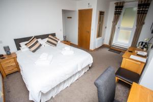 a bedroom with a large white bed and a desk at The Windmill Inn in Watchet