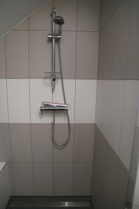 a shower with a hose on a tiled wall at Apartament Zimorodek Krościenko nad Dunajcem in Krościenko