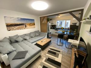 een woonkamer met een grijze bank en een keuken bij Pension Regenbogen in Triptis