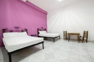 Habitación con 2 camas, sillas y pared púrpura. en OYO Casa Vieja,Ciudad Serdán,Museo La Magnolia en Ciudad Serdán