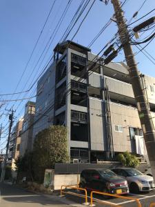 松戶的住宿－松戸 テイクファイブ - 水色1DK Nomad松戸宿015，前面有汽车停放的建筑