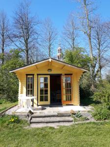 a small yellow house with a tower on top of it at Camping Boetn Toen Pieterburen in Pieterburen