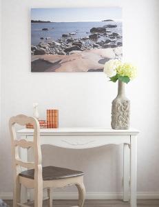 una scrivania bianca con un vaso di fiori e una sedia di B&B Villa Aurora a Hanko