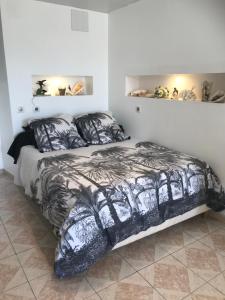 a bedroom with a bed with a black and white comforter at Charmant Studio meublé in Montignac-Charente