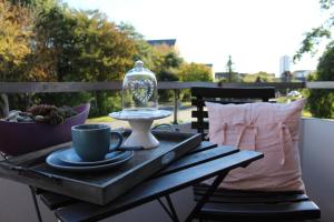 a table with a coffee cup and a glass dome on a balcony at Klein Erna (Apth.Holländerei) in Büsum