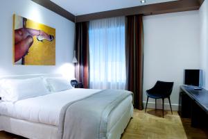 ein Hotelzimmer mit einem weißen Bett und einem Schreibtisch in der Unterkunft Hotel Principe Di Villafranca in Palermo