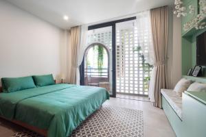 - une chambre avec un lit vert et une grande fenêtre dans l'établissement JooHouse Lux, à Hô-Chi-Minh-Ville