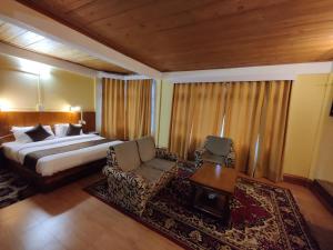 una camera con letto, sedia e tavolo di Pemaling Lords Inn Dirang a Dirang Dzong