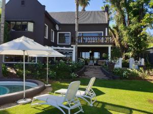 two chairs and an umbrella in front of a house at Le Must Residence in Upington