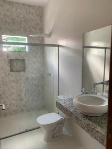 a bathroom with a sink and a toilet and a shower at Casa com piscina em c vermelha in Porto Seguro