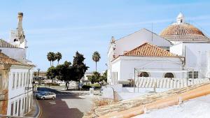 un edificio bianco con un'auto parcheggiata in una strada di Happy Terrace Downtown Tiny House 100% Portuguese a Faro