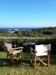 twee stoelen en een tafel in het gras bij Petroto Villas in Kiotari