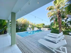 a deck with white lounge chairs and a swimming pool at Villa Koko Jan Thiel in Jan Thiel