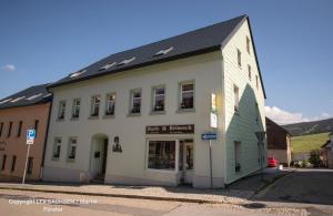 a white building on the corner of a street at Ferienwohnungen Haus Sebastian in Kurort Oberwiesenthal