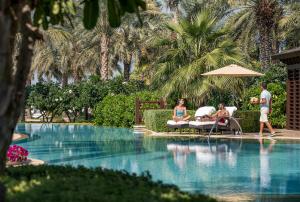 a group of people sitting around a swimming pool at Four Seasons Resort Dubai at Jumeirah Beach in Dubai