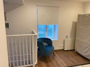 a baby room with a blue chair and a crib at cottage Philippe et Valérie in Silly-en-Gouffern